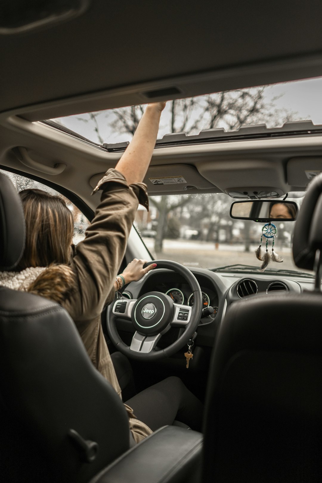woman-raising-her-right-hand-inside-black-and-brown-vehicle-ki1jt9bfwle